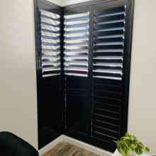 Black shutters on a window in a room.